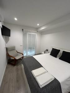 a bedroom with a large white bed and a chair at Alojamento Moinho d`Óbidos in Óbidos