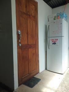 a wooden door in a room next to a refrigerator at Hogar tico-estadounidense cerca de aeropuerto in Alajuela