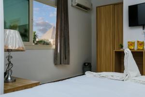 um quarto com uma cama branca e uma janela em Pyramids Paradise View Inn Hotel em Cairo