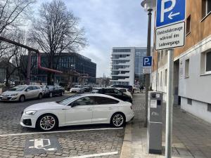 un coche blanco estacionado en una calle al lado de un parquímetro en Wohnung 2 neben Warschauer Platz und Spree, en Berlín
