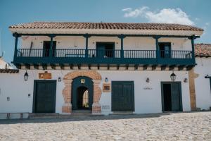 a white building with a balcony and two doors at Hotel La Corada in Villa de Leyva