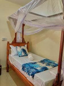 1 dormitorio con 1 cama con dosel en SHIMBA SPRINGS MBUYU. ( Malindi), en Malindi