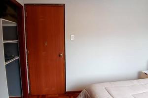 a bedroom with a bed and a wooden door at Estudio a estrenar en Miraflores in La Paz