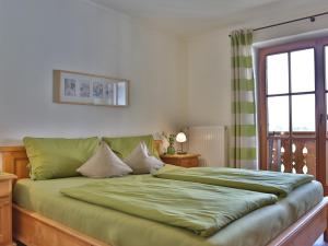a bedroom with a green bed with a window at Sotterhof - Chiemgau Karte in Inzell