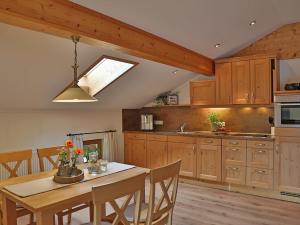 a kitchen with wooden cabinets and a table with chairs at Sotterhof - Chiemgau Karte in Inzell