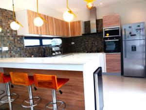 a kitchen with a counter with two chairs and a refrigerator at Palms Haven - Mauritius - Modern and luxury vacation home in Phoenix