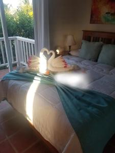 dwa łabędzie leżą na łóżku w sypialni w obiekcie Sapphire Beach Condo w mieście San Pedro