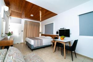 Habitación de hotel con cama, escritorio y TV. en Helios 2, en Pafos