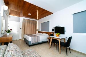 une chambre d'hôtel avec un lit, un bureau et une télévision dans l'établissement Helios 2, à Paphos