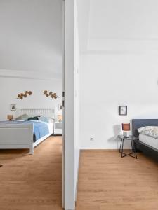 a white bedroom with two beds and a table at sparkasse platz 8 in Stockerau