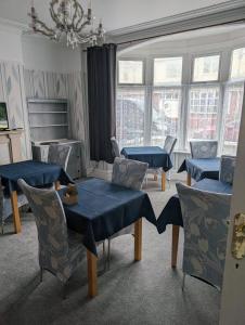 una sala de estar con mesas y sillas azules y ventanas en Rossdene House, en Blackpool