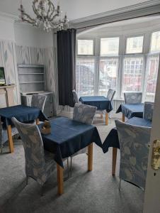 una sala de estar con mesas y sillas azules y ventanas en Rossdene House en Blackpool