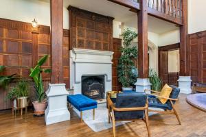 a living room with a fireplace and wooden walls at 9 Bedrooms Grand Manor House Near Bath, Sleeps 26 in Seend