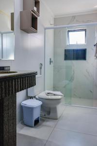 a bathroom with a toilet and a glass shower at Pousada Refugio Costeiro in Bombinhas