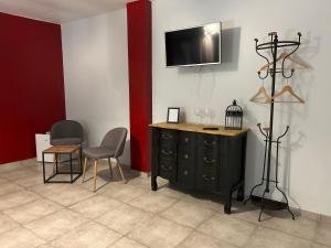 a room with a black dresser and a tv on a wall at La Fralinette in Fralignes