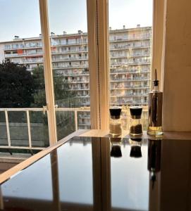 a glass table with three candles in a room with a window at Logement Woluwé in Brussels