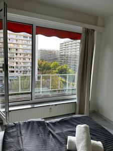 een slaapkamer met een bed en een groot raam bij Logement Woluwé in Brussel