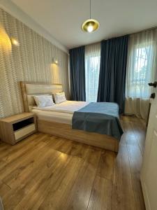 a bedroom with a bed with blue sheets and wooden floors at Hotel Lile in Tbilisi City