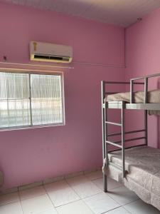 Cette chambre est dotée de 2 lits superposés et d'un mur rose. dans l'établissement Kit net CN, à Ananindeua