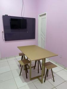 a table with two chairs and a tv on a wall at Kit net CN in Ananindeua