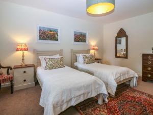a bedroom with two beds and a chair and a mirror at Steading Cottage - Craigievar Castle in Alford