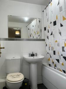 a bathroom with a sink and a toilet and a mirror at City Airport Apartment in Wythenshawe