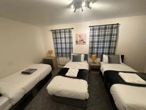 two beds in a room with two windows at City Airport Apartment in Wythenshawe