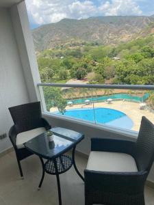a balcony with a table and chairs and a pool at Hermoso y acogedor apartamento! in Santa Fe de Antioquia