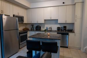 a kitchen with white cabinets and a stainless steel refrigerator at The Tranquil Retreat in Toronto