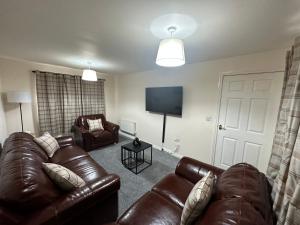 ein Wohnzimmer mit Ledermöbeln und einem Flachbild-TV in der Unterkunft City Airport Apartment in Wythenshawe