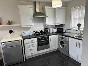 La cuisine est équipée de placards blancs et d'un four avec plaques de cuisson. dans l'établissement City Airport Apartment, à Wythenshawe