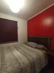 1 dormitorio con cama y pared roja en Hospedaje Santa Maria y POP, en Osorno