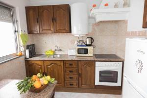 cocina con armarios de madera, fregadero y microondas en Casa 'Saudade' en Moura