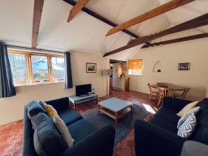 ein Wohnzimmer mit blauen Sofas und einem Tisch in der Unterkunft Little Owl Cottage in Saxmundham