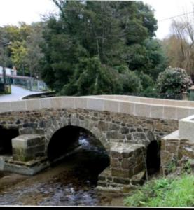 a stone bridge over a river with a bridge at PISO DEL PARQUE 2 in Santiago de Compostela