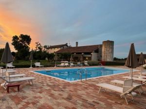 a swimming pool with chairs and umbrellas next to a house at Agrimargherita in Caorle +26 photos