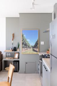 a kitchen with a painting of a vineyard on the wall at Apartamento no coração de Bento Gonçalves in Bento Gonçalves
