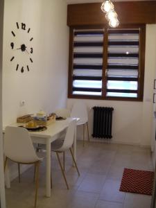 uma sala de jantar com mesa e cadeiras e um relógio em Appartamento ARCOBALENO em Tirano