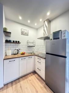 a kitchen with white cabinets and a stainless steel refrigerator at Na Kamieńcu domki in Rzyki