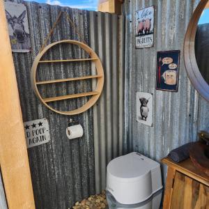 a bathroom with a toilet and signs on the wall at Two Little Piggies Glamping 