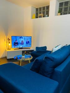 uma sala de estar com um sofá azul e uma televisão em Agréable logement 2 chambres em Saint-Saulve