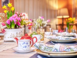 una mesa con platos, tazas y flores. en Hill House en Bath