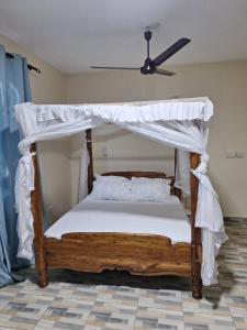 Schlafzimmer mit Himmelbett und weißer Bettwäsche in der Unterkunft Le Grande Haven in Lunga-Lunga