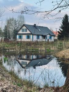 una casa se refleja en un cuerpo de agua en Gościniec Pod Dębami I, 