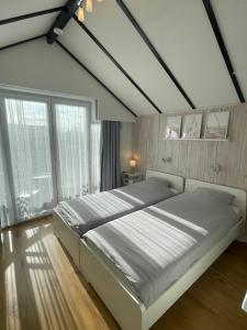 a bedroom with a large bed and a large window at Appartement met prachtig polderzicht in De Haan