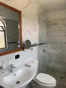 a bathroom with a sink and a toilet and a mirror at Hotel y Restaurante Castillo de los Altos in Quetzaltenango