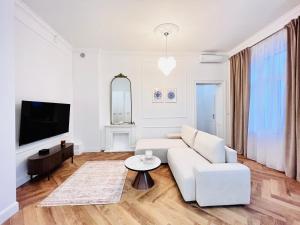 Apartamenty Lubin - Noclegi Lubin في لوبين: غرفة معيشة بيضاء مع أريكة بيضاء وطاولة
