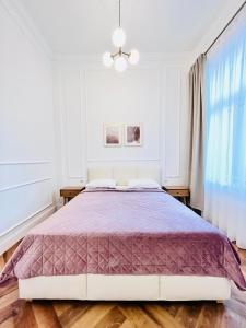 a bedroom with a large bed with a purple comforter at Apartamenty Lubin - Noclegi Lubin in Lubin