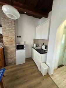 a kitchen with white cabinets and a sink and a microwave at Karaván guest house in Hollókő