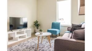 a living room with a couch and a tv and a table at Stunning Nulu 1BR CozySuites 02 in Louisville
